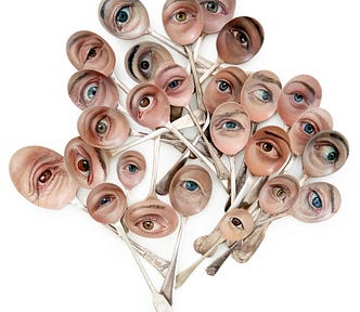 A cluster of roughly two dozen metal spoons on which human eyes have been painted