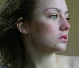 A woman looking distant, in pain, and crying
