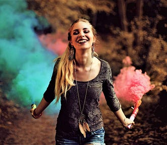 smiling girl with long brown hair holding green and pink flares