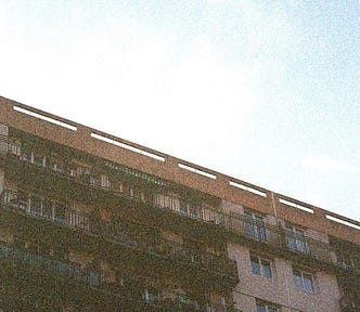 Film photo of building’s top floors and blue sky