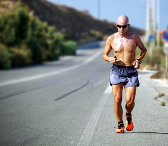 A runner in a pair of shorts running beside a long straight road