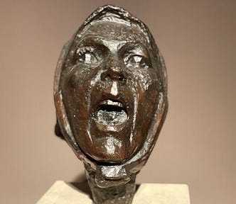 Sculpture of a woman’s head with her mouth open in a yell or scream.