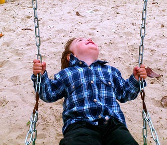 Happy little boy on a swing at the playground