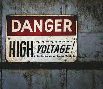 Sign on gray wall that reads DANGER: HIGH VOLTAGE!