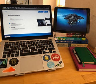 Dual monitor setup with laptop and iPad placed on a pile of 4 books, connected via Duet Display app.
