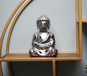 Charming statue of a sitting Buddha on a shelf