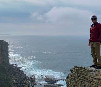 The author on top of a cliff with the ocean on the background.