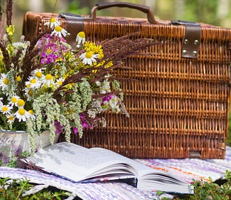 A picnic basket, a book, & a bouquet of flowers.