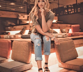 thoughtful girl with long blonde hair sitting on cushion