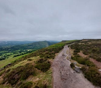 A winding trail disappearing through green hills.