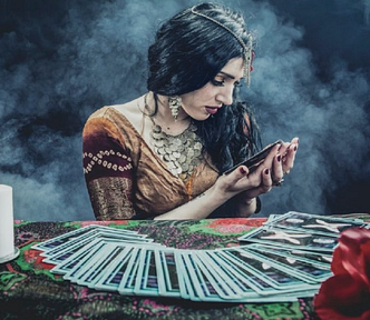 A psychic has tarot cards fanned out in front of her as she examines the one in her hand