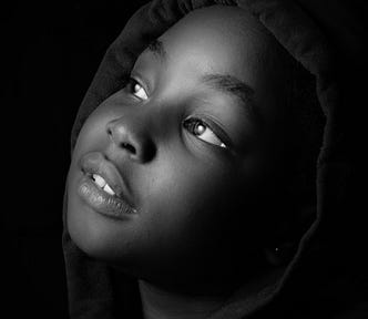 black and white closeup photo of a girl looking up and to the side, black background