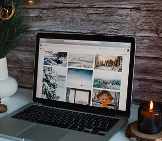 The image shows a laptop on a desk surrounded by winter and Christmas ornaments such as a candle and pine combs.