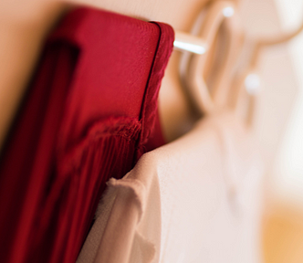 A red garment and a white garment hang against a wall.