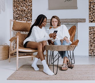 Two women look at a phone inside a gorgeous Scandinavian house.