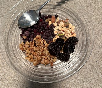 A mixture of walnuts, almonds, peanuts, pistachios, prunes and blueberries, ready to add chia seeds and skim milk.