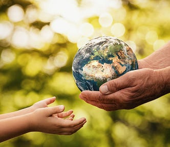 A pair of hands of an older person hands a miniature globe to a child