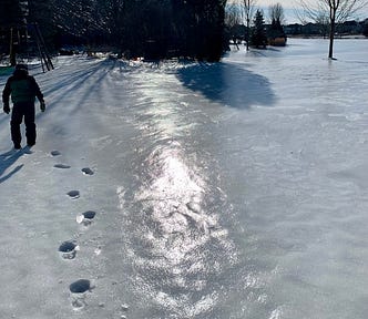 Ice-coated snow and a boy in snow suit makes footprints in the snow.