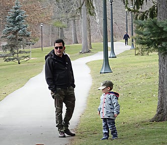 man and small boy standing in park