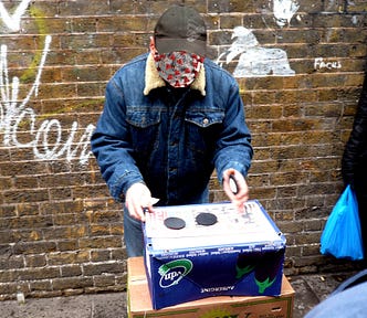 A three-card monte fraudster; his face has been replaced by a covid molecule.