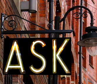 Sign in a street with the word “Ask” on it