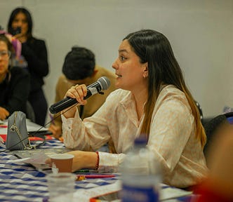 Woman at an event holding a microphone while talking.
