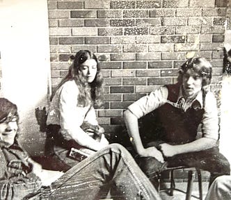 Three teenagers (two male and one female) sit on chairs in a bricked in room