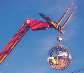 A forklift holds up a mirrored ball.