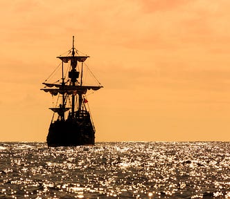 A tall ship sillhoutted against an orange sky