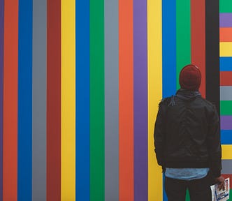 Man faces rainbow colored striped wall