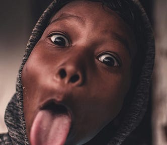 A picture of a black young person with tongue out in mockery