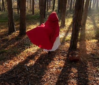 Woman in a handmaid’s tale style red robe running through a forest