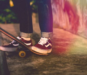 Photo of red sneakers stepping on a skateboard at the top of a skate ramp
