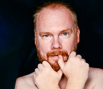 A caucasian middle-aged guy with red hair and beard looks uncomfortable