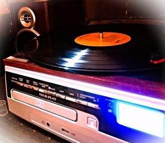 Record player with a CD drive in front and a vinyl record on top with the player arm on the record.