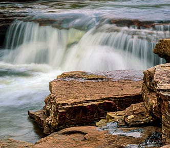 A waterfall, with a soft water effect, and rocks in the foreground, at Ohiopyle State Park in Pennsylvania