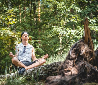 A man practices self-love by meditating in nature.