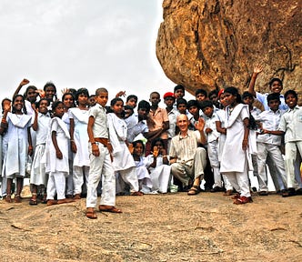 In the group photo, the author, József Manhertz, is laughing and waving in the company of about 50 Indian children. Children around the age of ten wear white school uniforms.