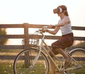 A girl wearing a VR helmet while riding a bike. This seems like a really bad idea.