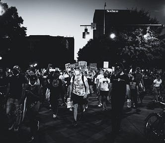 A black and white photo of a protest. SurvivingTomorrow.org