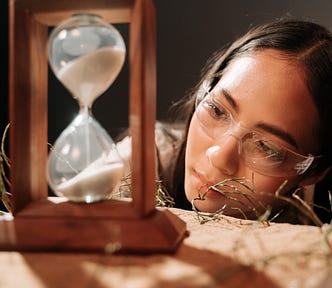 woman looks at a sand hourglass.