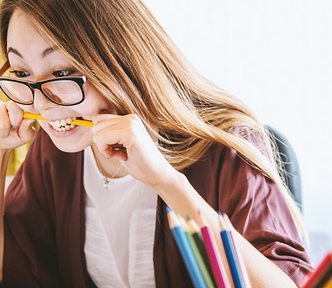 A young woman with a pencil between her teeth