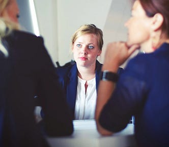A young woman facing out two other women in a business meeting.