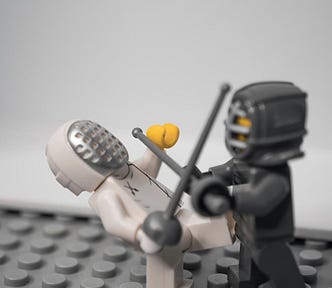 Two lego figures fencing