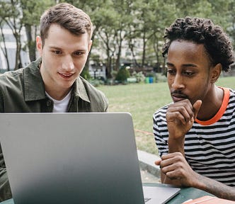 two men are looking in laptop
