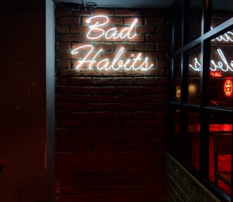 Bad Habits sign on a bare wall.