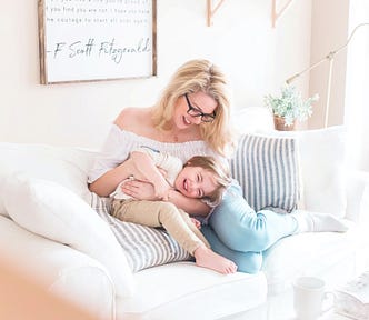 mother and child on white couch playing and laughing