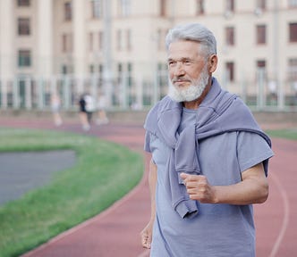 An older bearded ban jogs on a track