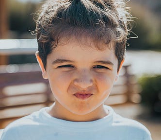 A photo of a beautiful young child squeezing her face in sadness and stubborness, as she plans to try again at that thing she had been refused.