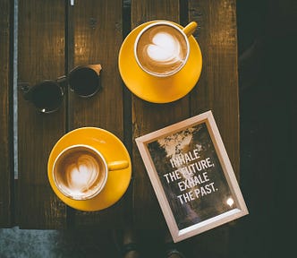 Coffee cups and a plaque with the text “Inhale the future, exhale the past”
